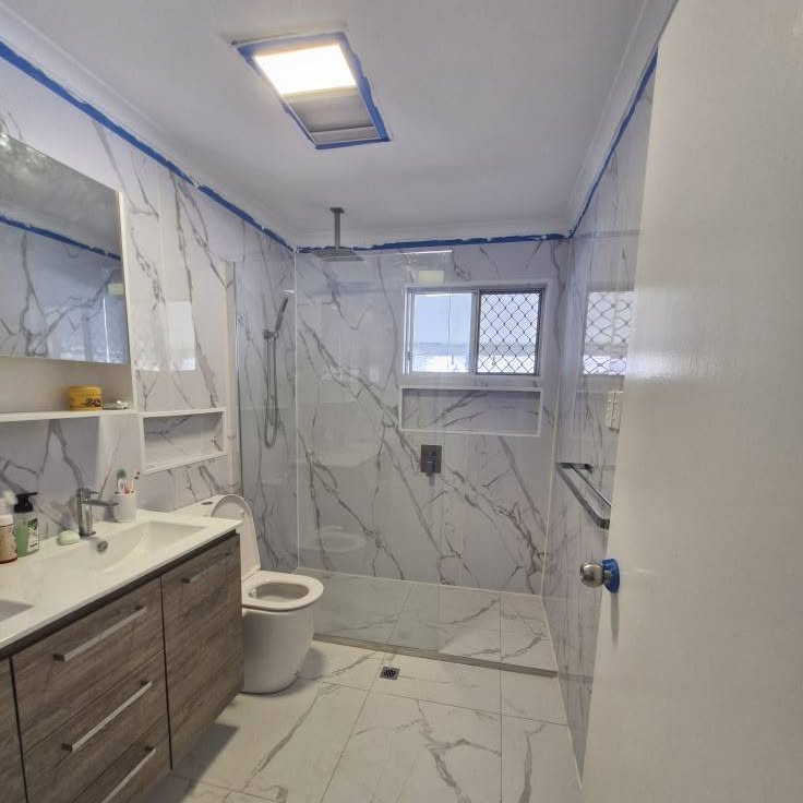Wide view of the renovated bathroom with shower screen, grab rail and vanity
