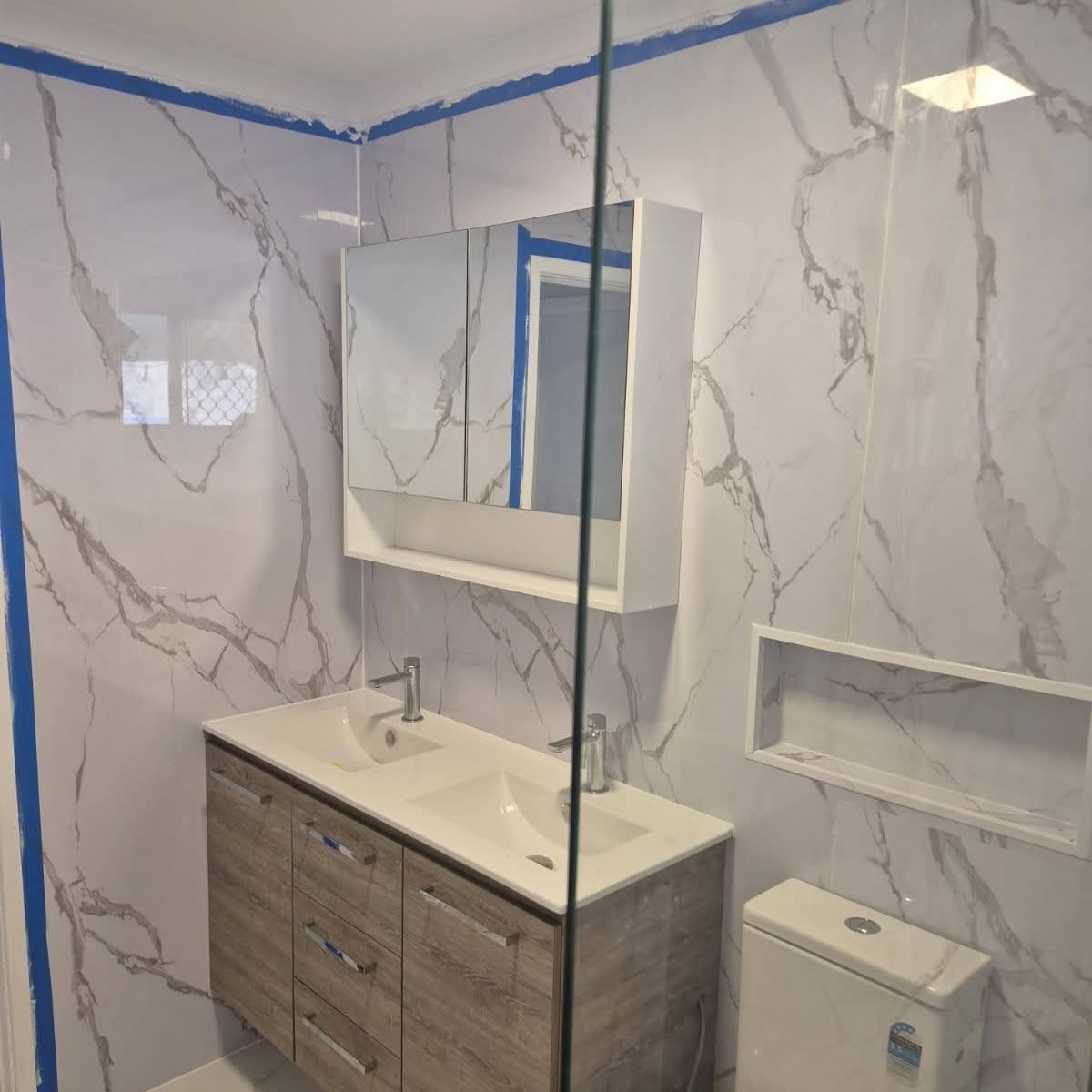 Finished bathroom with double-basin timber vanity, mirrored cabinet and marble-look tiles